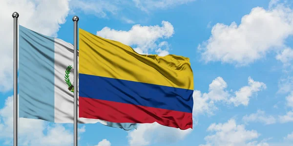 Bandera de Guatemala y Colombia ondeando en el viento contra el cielo azul nublado blanco juntos. Concepto diplomático, relaciones internacionales . — Foto de Stock