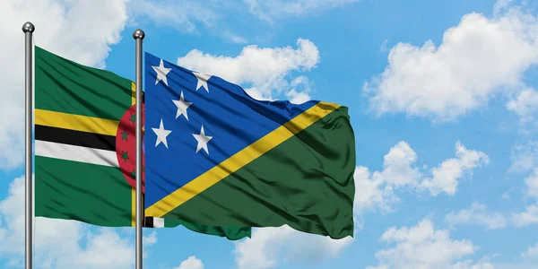 Bandera de Dominica y las Islas Salomón ondeando en el viento contra el cielo azul nublado blanco juntos. Concepto diplomático, relaciones internacionales . — Foto de Stock