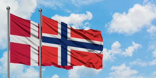 Bandera de Dinamarca y Bouvet Islands ondeando en el viento contra el cielo azul nublado blanco juntos. Concepto diplomático, relaciones internacionales . — Foto de Stock