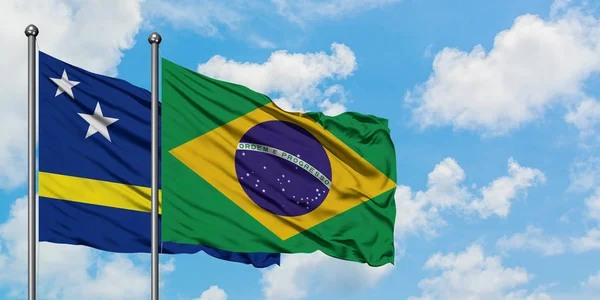 Curaçao e a bandeira do Brasil agitando no vento contra o céu azul nublado branco juntos. Conceito de diplomacia, relações internacionais . — Fotografia de Stock
