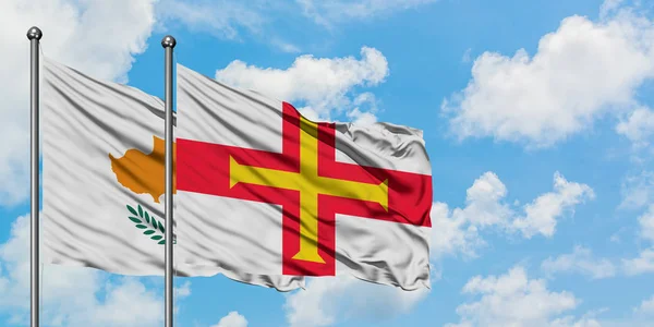 Bandera de Chipre y Guernsey ondeando en el viento contra el cielo azul nublado blanco juntos. Concepto diplomático, relaciones internacionales . — Foto de Stock