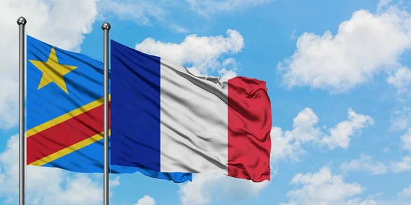 Bandera del Congo y Francia ondeando en el viento contra el cielo azul nublado blanco juntos. Concepto diplomático, relaciones internacionales . — Foto de Stock