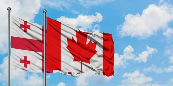 Bandera de Georgia y Canadá ondeando en el viento contra el cielo azul nublado blanco juntos. Concepto diplomático, relaciones internacionales . — Foto de Stock
