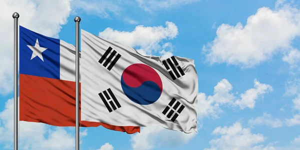 Η σημαία της Χιλής και της Νότιας Κορέας κουνώντας τον άνεμο ενάντια στον λευκό θολό γαλάζιο ουρανό μαζί. Φιλοσοφία της διπλωματίας, διεθνείς σχέσεις. — Φωτογραφία Αρχείου