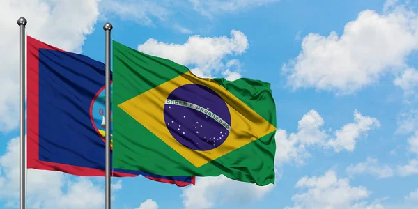 Bandera de Guam y Brasil ondeando en el viento contra el cielo azul nublado blanco juntos. Concepto diplomático, relaciones internacionales . —  Fotos de Stock