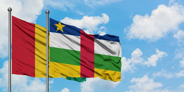 Bandera de Guinea y República Centroafricana ondeando en el viento contra el cielo azul nublado blanco juntos. Concepto diplomático, relaciones internacionales . — Foto de Stock