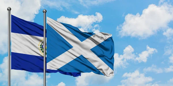 El Salvador and Scotland flag waving in the wind against white cloudy blue sky together. Diplomacy concept, international relations.