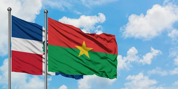 Bandera de República Dominicana y Burkina Faso ondeando en el viento contra el cielo azul nublado blanco juntos. Concepto diplomático, relaciones internacionales . — Foto de Stock