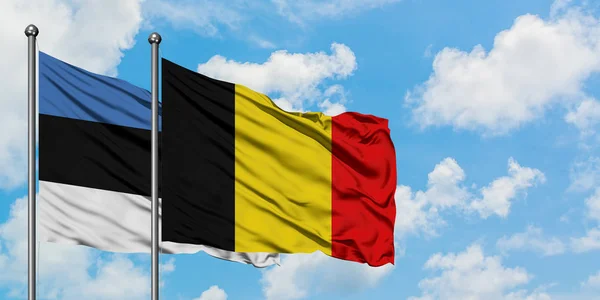 Bandera de Estonia y Bélgica ondeando en el viento contra el cielo azul nublado blanco juntos. Concepto diplomático, relaciones internacionales . — Foto de Stock
