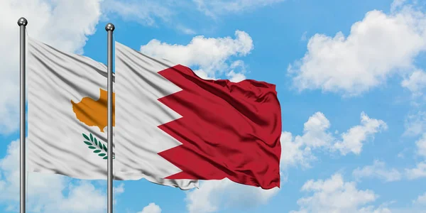 Cypern och Bahrain flagga vifta i vinden mot vit grumlig blå himmel tillsammans. Diplomatisk koncept, internationella relationer. — Stockfoto