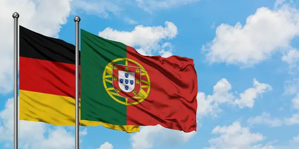 Bandera de Alemania y Portugal ondeando en el viento contra el cielo azul nublado blanco juntos. Concepto diplomático, relaciones internacionales . — Foto de Stock