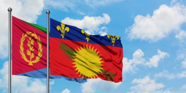Eritre ve Guadeloupe bayrağı birlikte beyaz bulutlu mavi gökyüzüne karşı rüzgarda sallayarak. Diplomasi kavramı, uluslararası ilişkiler.