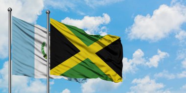 Guatemala ve Jamaika bayrağı birlikte beyaz bulutlu mavi gökyüzüne karşı rüzgarda sallayarak. Diplomasi kavramı, uluslararası ilişkiler.