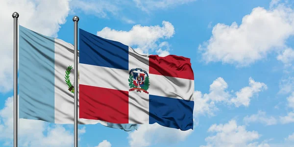 Bandera de Guatemala y República Dominicana ondeando en el viento contra el cielo azul nublado blanco juntos. Concepto diplomático, relaciones internacionales . — Foto de Stock