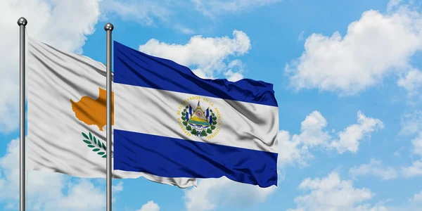 Cypr i flaga El Salvador machając w wiatr przed białym zachmurzone błękitne niebo razem. Koncepcja dyplomacji, stosunki międzynarodowe. — Zdjęcie stockowe