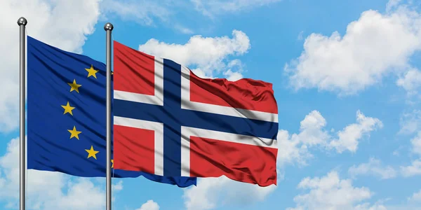 Bandera de la Unión Europea y Noruega ondeando en el viento contra el cielo azul nublado blanco juntos. Concepto diplomático, relaciones internacionales . — Foto de Stock