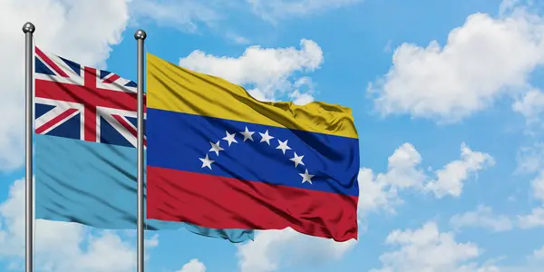 Фіджі і Венесуела прапор розмахував вітром проти білого хмарного синього неба разом. Концепція дипломатії, міжнародні відносини. — стокове фото