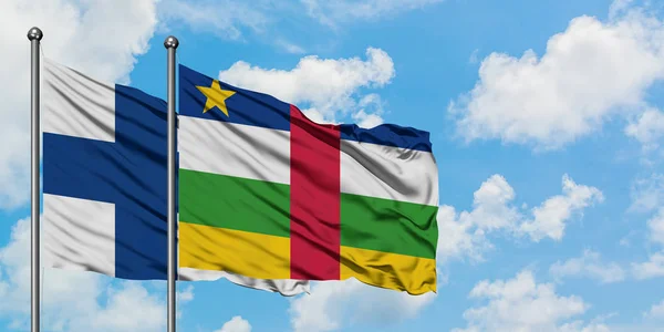 Bandera de Finlandia y República Centroafricana ondeando en el viento contra el cielo azul nublado blanco juntos. Concepto diplomático, relaciones internacionales . — Foto de Stock