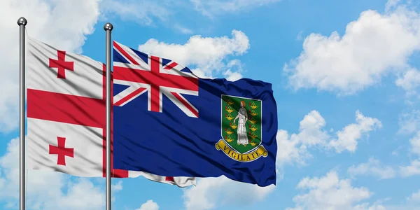 Bandera de Georgia y las Islas Vírgenes Británicas ondeando en el viento contra el cielo azul nublado blanco juntos. Concepto diplomático, relaciones internacionales . — Foto de Stock