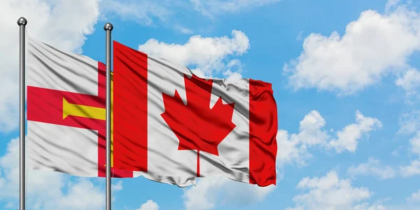 Bandera de Guernsey y Canadá ondeando en el viento contra el cielo azul nublado blanco juntos. Concepto diplomático, relaciones internacionales . — Foto de Stock