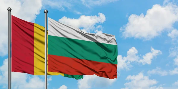 Bandera de Guinea y Bulgaria ondeando en el viento contra el cielo azul nublado blanco juntos. Concepto diplomático, relaciones internacionales . — Foto de Stock
