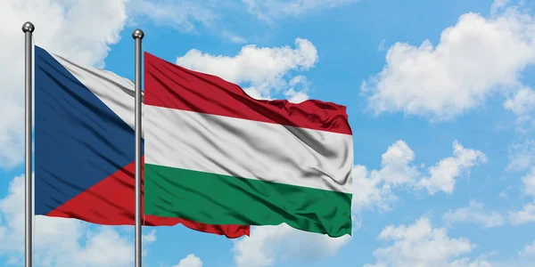 Bandera de la República Checa y Hungría ondeando en el viento contra el cielo azul nublado blanco juntos. Concepto diplomático, relaciones internacionales . — Foto de Stock