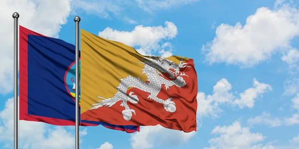Guam e a bandeira do Butão agitando no vento contra o céu azul nublado branco juntos. Conceito de diplomacia, relações internacionais . — Fotografia de Stock