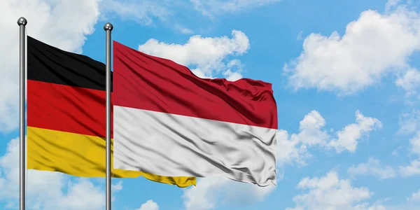 Bandera de Alemania e Indonesia ondeando en el viento contra el cielo azul nublado blanco juntos. Concepto diplomático, relaciones internacionales . —  Fotos de Stock