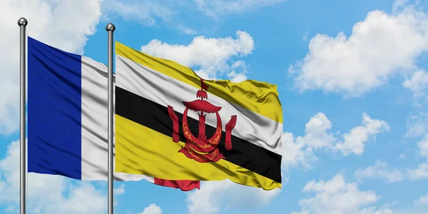Франція і Бруней прапор розмахував вітром проти білого хмарного синього неба разом. Концепція дипломатії, міжнародні відносини. — стокове фото