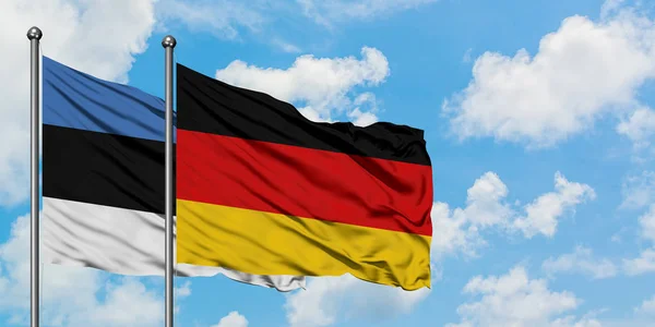 Bandera de Estonia y Alemania ondeando en el viento contra el cielo azul nublado blanco juntos. Concepto diplomático, relaciones internacionales . —  Fotos de Stock