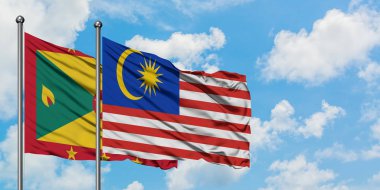 Grenada ve Malezya bayrağı birlikte beyaz bulutlu mavi gökyüzüne karşı rüzgarda sallayarak. Diplomasi kavramı, uluslararası ilişkiler.