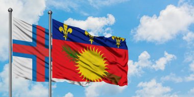 Faroe Adaları ve Guadeloupe bayrağı birlikte beyaz bulutlu mavi gökyüzüne karşı rüzgarda sallayarak. Diplomasi kavramı, uluslararası ilişkiler.