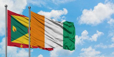 Grenada ve Fildişi Sahili bayrağı birlikte beyaz bulutlu mavi gökyüzüne karşı rüzgarda sallayarak. Diplomasi kavramı, uluslararası ilişkiler.