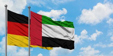 Almanya ve Birleşik Arap Emirlikleri bayrağı birlikte beyaz bulutlu mavi gökyüzüne karşı rüzgarsal sallayarak. Diplomasi kavramı, uluslararası ilişkiler.