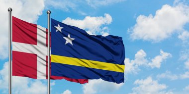 Danimarka ve Curacao bayrağı birlikte beyaz bulutlu mavi gökyüzüne karşı rüzgarda sallayarak. Diplomasi kavramı, uluslararası ilişkiler.