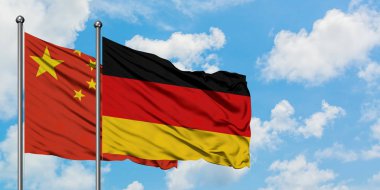 Çin ve Almanya bayrağı birlikte beyaz bulutlu mavi gökyüzüne karşı rüzgarsal sallayarak. Diplomasi kavramı, uluslararası ilişkiler.