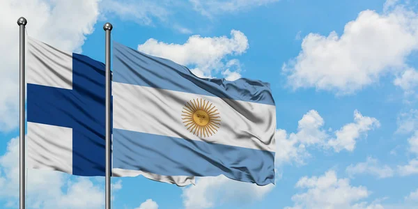 Bandera de Finlandia y Argentina ondeando en el viento contra el cielo azul nublado blanco juntos. Concepto diplomático, relaciones internacionales . — Foto de Stock