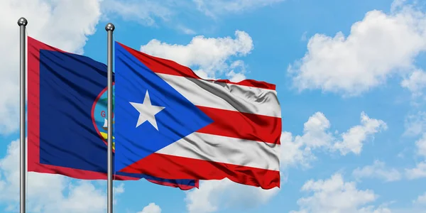 Guam und Puerto Rico schwenken gemeinsam die Flagge im Wind gegen den wolkenverhangenen blauen Himmel. Diplomatie-Konzept, internationale Beziehungen. — Stockfoto