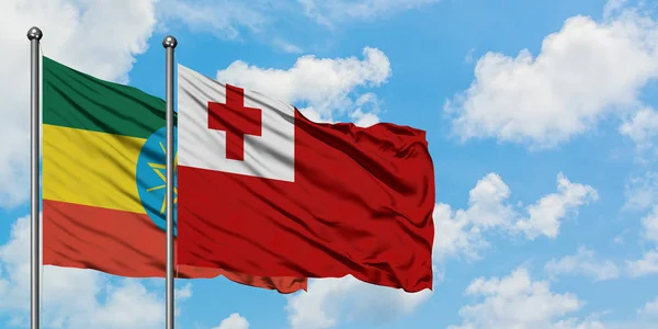 Bandera de Etiopía y Tonga ondeando en el viento contra el cielo azul nublado blanco juntos. Concepto diplomático, relaciones internacionales . —  Fotos de Stock