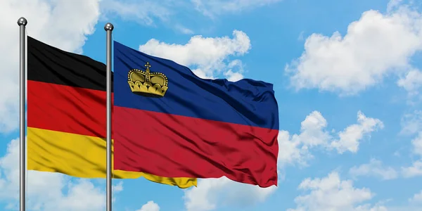 Bandeira da Alemanha e Liechtenstein agitando no vento contra o céu azul nublado branco juntos. Conceito de diplomacia, relações internacionais . — Fotografia de Stock