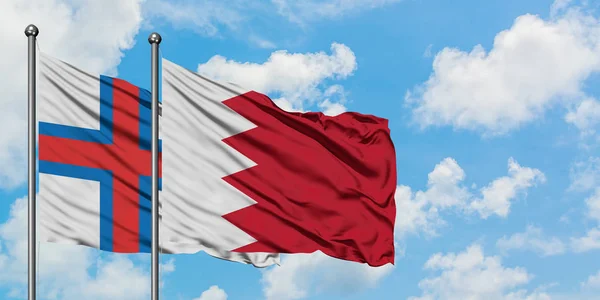 Bandera de las Islas Feroe y Bahréin ondeando en el viento contra el cielo azul nublado blanco juntos. Concepto diplomático, relaciones internacionales . — Foto de Stock