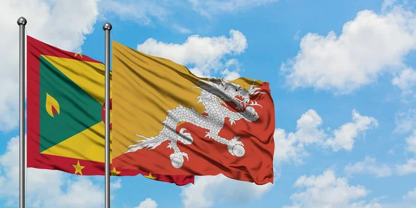 Bandera de Granada y Bután ondeando en el viento contra el cielo azul nublado blanco juntos. Concepto diplomático, relaciones internacionales . — Foto de Stock