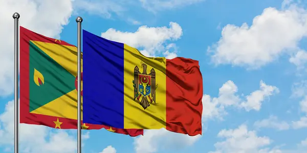Bandera de Granada y Moldavia ondeando en el viento contra el cielo azul nublado blanco juntos. Concepto diplomático, relaciones internacionales . — Foto de Stock