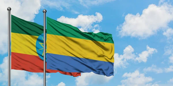 Bandera de Etiopía y Gabón ondeando en el viento contra el cielo azul nublado blanco juntos. Concepto diplomático, relaciones internacionales . — Foto de Stock