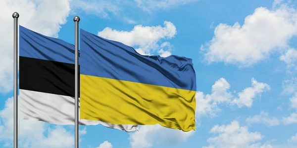 Estonsko a ukrajinská vlajka mávali ve větru proti bíle zatažené modré obloze. Diplomacie, mezinárodní vztahy. — Stock fotografie
