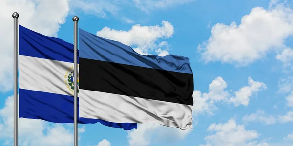 El Salvador e a bandeira da Estônia agitando no vento contra o céu azul nublado branco juntos. Conceito de diplomacia, relações internacionais . — Fotografia de Stock