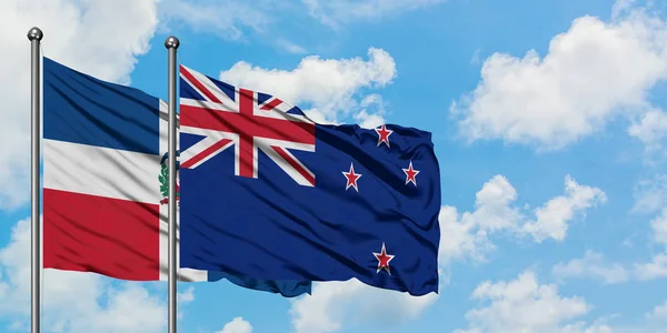 多米尼加共和国和新西兰国旗在风中飘扬，与白云蓝天相一起。外交概念、国际关系. — 图库照片