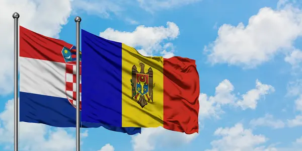 Bandera de Croacia y Moldavia ondeando en el viento contra el cielo azul nublado blanco juntos. Concepto diplomático, relaciones internacionales . — Foto de Stock