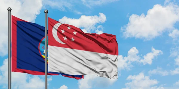 Guam and Singapore flag waving in the wind against white cloudy blue sky together. Diplomacy concept, international relations. — Stock Photo, Image