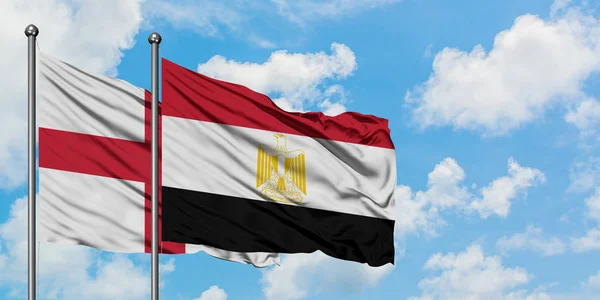 Bandera de Inglaterra y Egipto ondeando en el viento contra el cielo azul nublado blanco juntos. Concepto diplomático, relaciones internacionales . — Foto de Stock